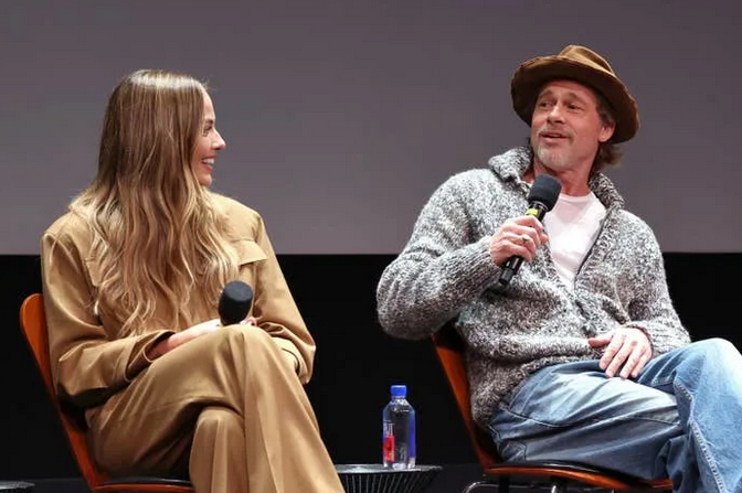 Margot Robbie and Brad Pitt sitting in chairs